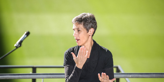 Barrierefreiheit Eine Gebärdendolmetscherin steht neben einem Mikrofon.