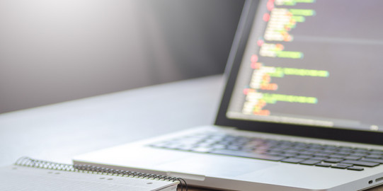 Tools Foto eines Laptops und Notizbuches auf einem Schreibtisch.